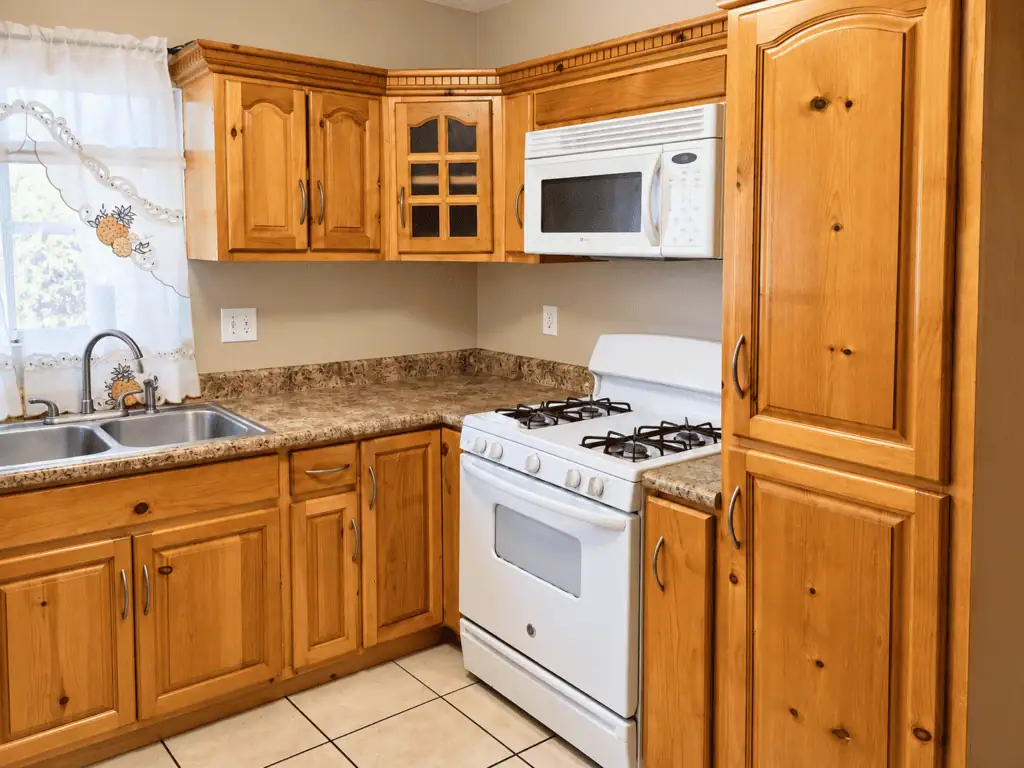 Modern kitchen with wooden cabinets, stove, microwave, and granite countertops.