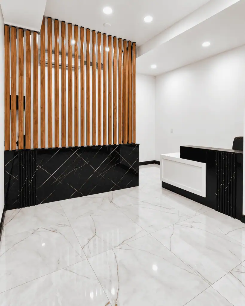 Contemporary office reception with wooden slats and marble flooring.